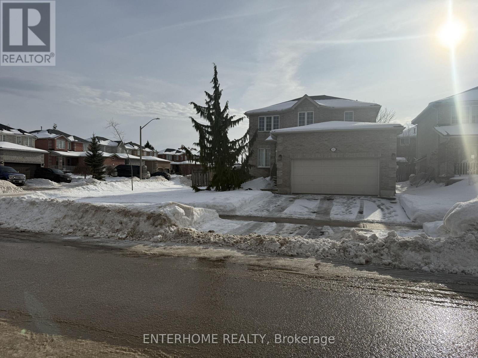 A real estate sign in front of a house with snow on the ground.