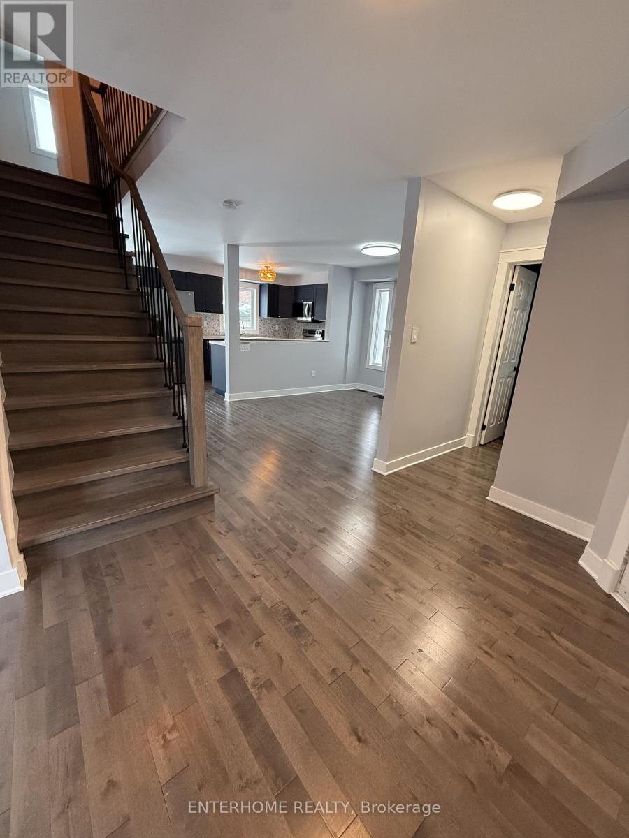 A spacious living room with wood flooring and a staircase.
