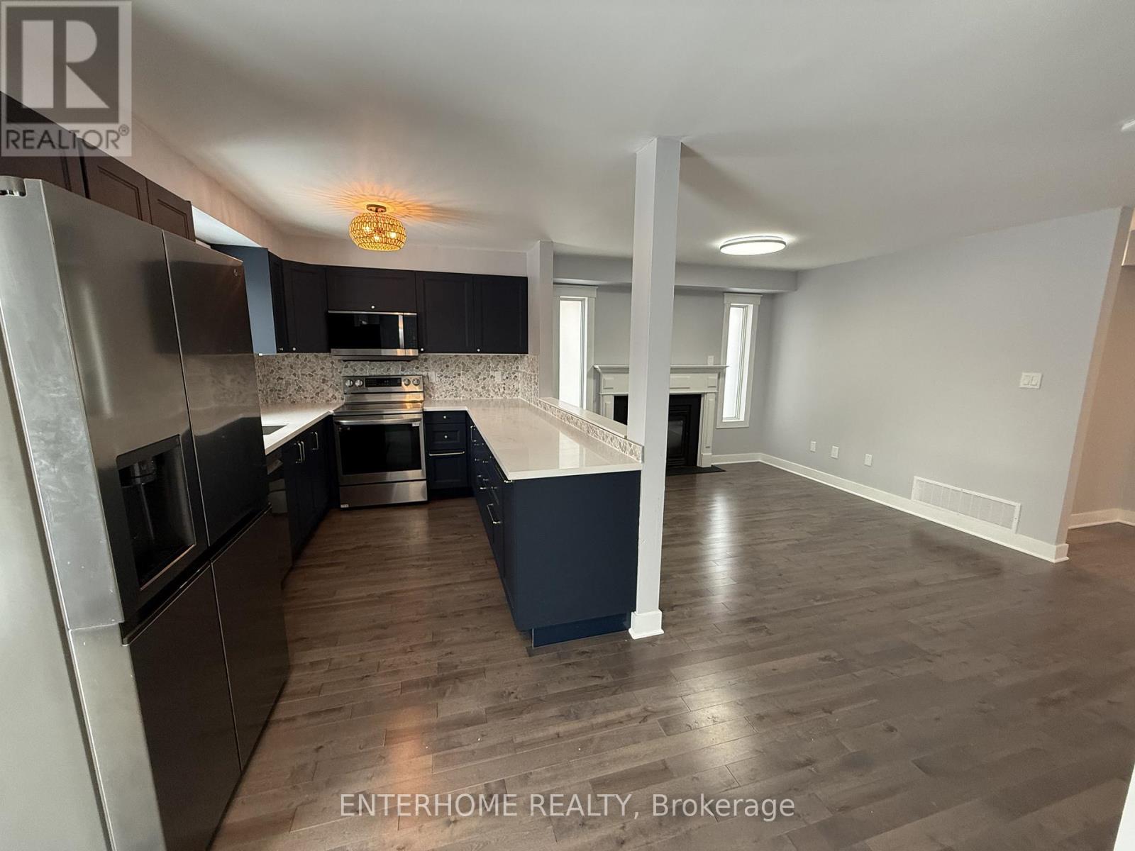 A kitchen with dark wood floors and stainless steel appliances.