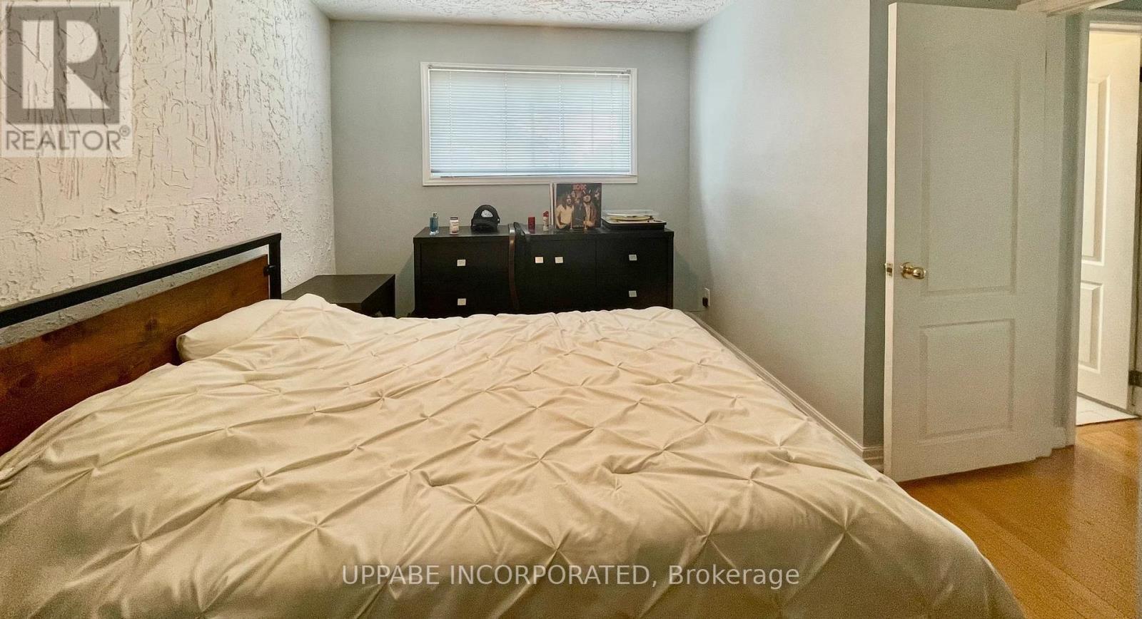 A bedroom with a bed, nightstand, and a dresser with a mirror.