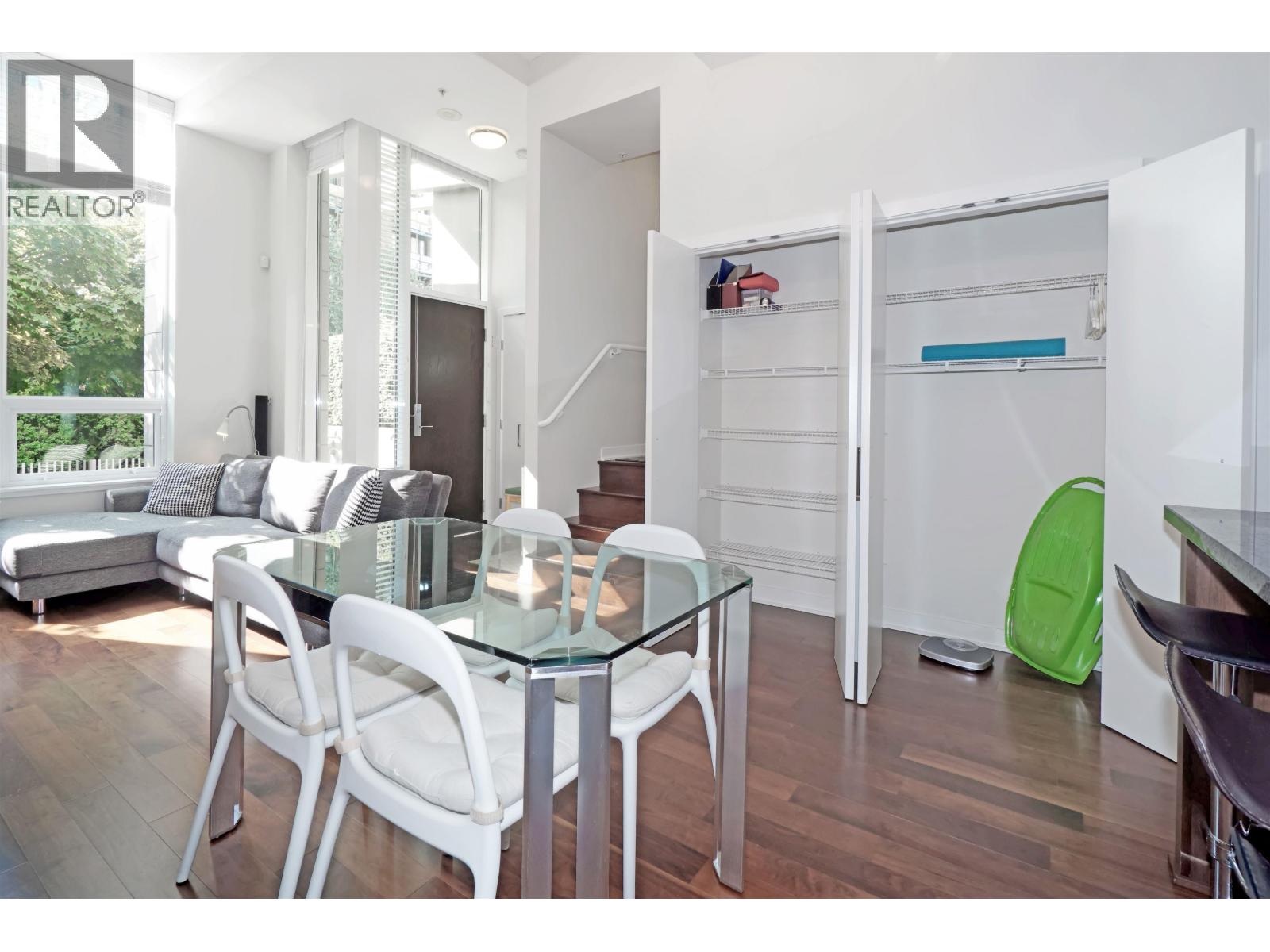 A modern dining room with a glass table and white chairs.