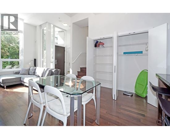 A modern dining room with a glass table and white chairs.