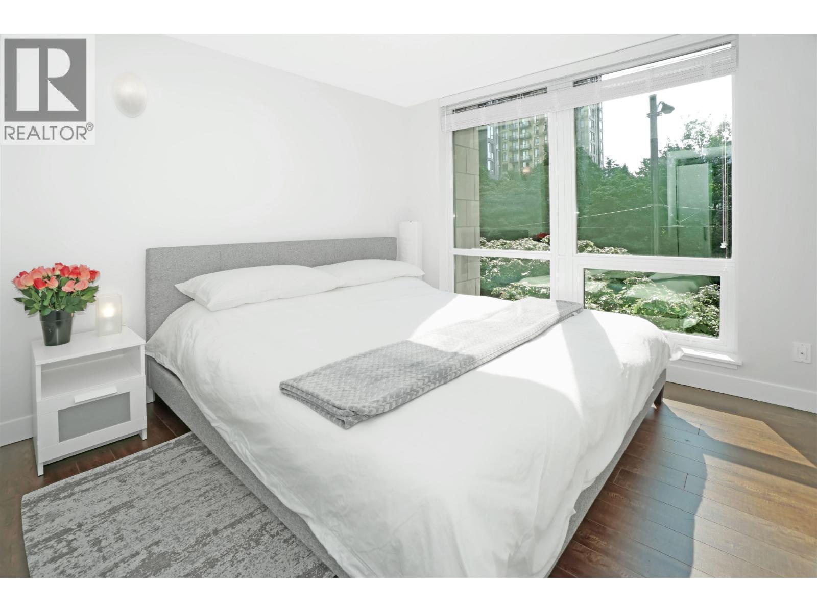 A bedroom with a large bed and a window overlooking a garden.