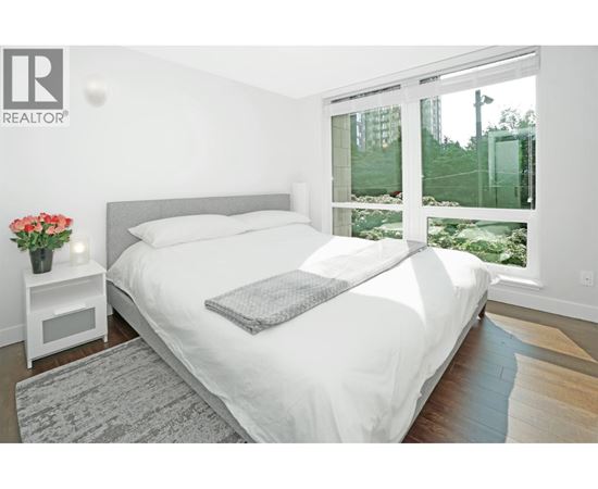 A bedroom with a large bed and a window overlooking a garden.