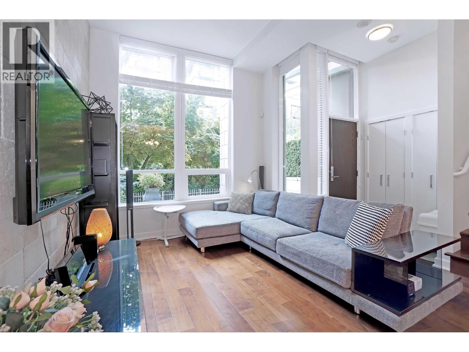 A modern living room with a grey sofa and a television on the wall.