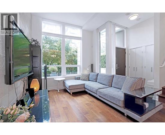 A modern living room with a grey sofa and a television on the wall.