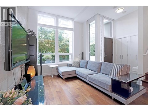 A modern living room with a grey sofa and a television on the wall.