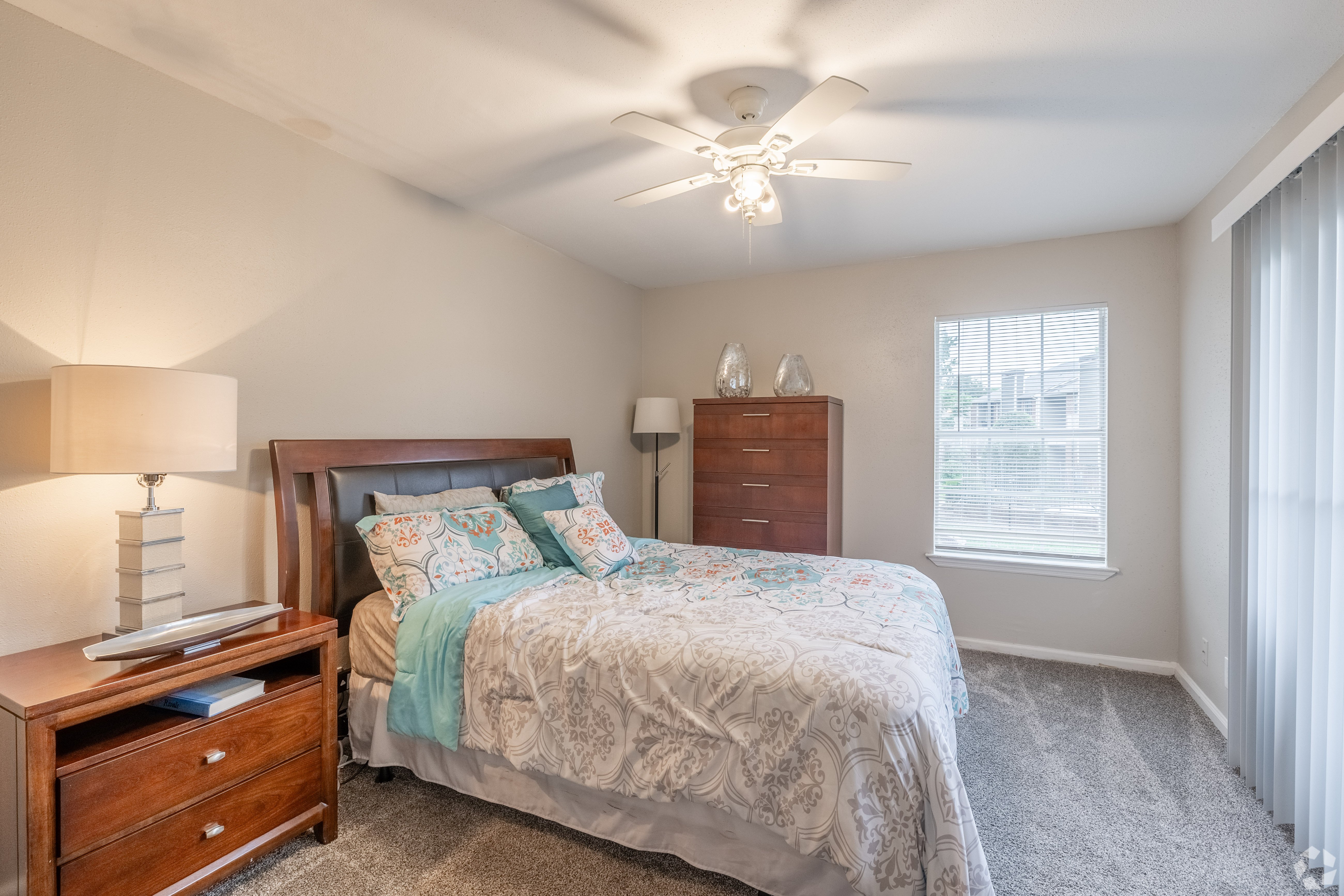 A bedroom with a bed, nightstand, and window.