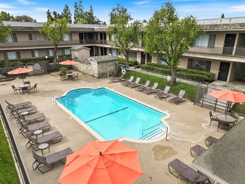 A pool surrounded by chairs and umbrellas in front of a building.