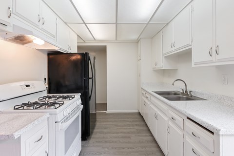 A kitchen with white cabinets and a black refrigerator.