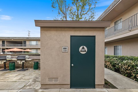 A beige building with a green door and a sign on it.