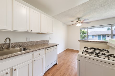 A kitchen with white cabinets and a stove top oven.