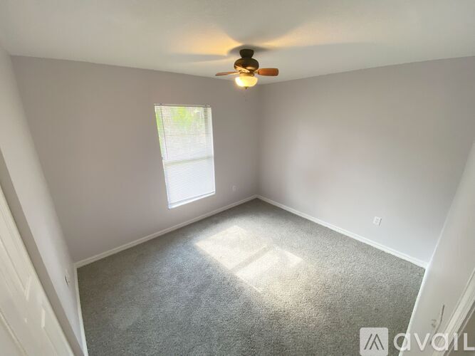 A room with a ceiling fan and a window letting in sunlight.