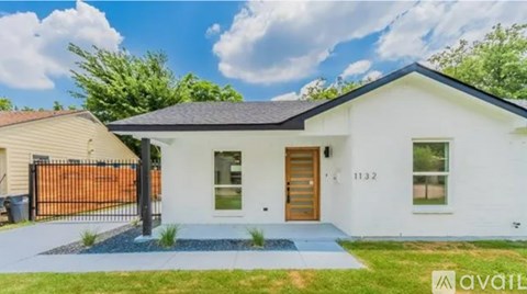 A white house with a black roof and a brown gate is for sale.