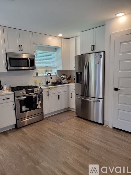 A kitchen with a stainless steel refrigerator and wooden flooring.
