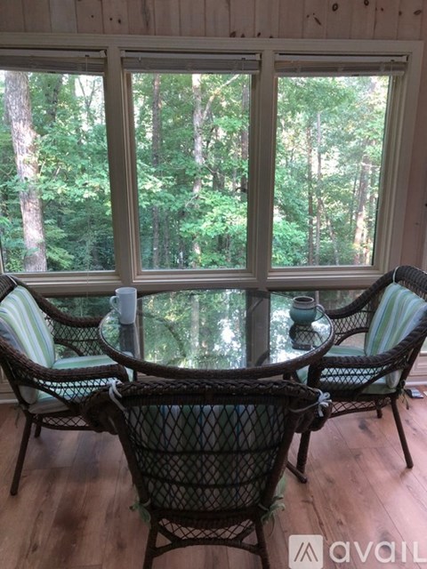 A table with chairs in front of a window with a view of trees.