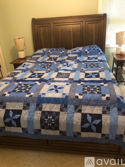 A bed with a blue and white quilt and a wooden headboard.