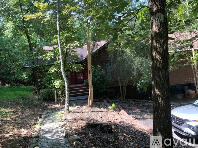 A house is surrounded by trees and a stone pathway leads to the front door.