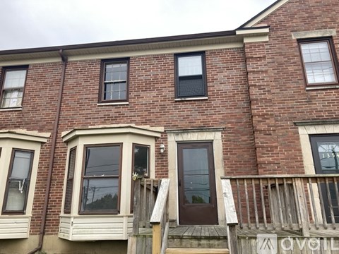 A red brick house with a white porch and a brown door.