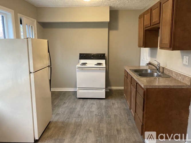 A kitchen with a white fridge, a white dishwasher, and brown cabinets.