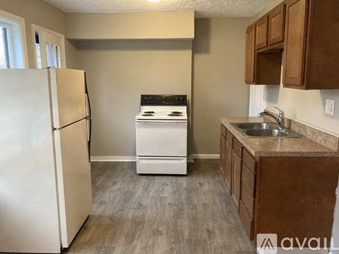A kitchen with a white fridge, a white dishwasher, and brown cabinets.