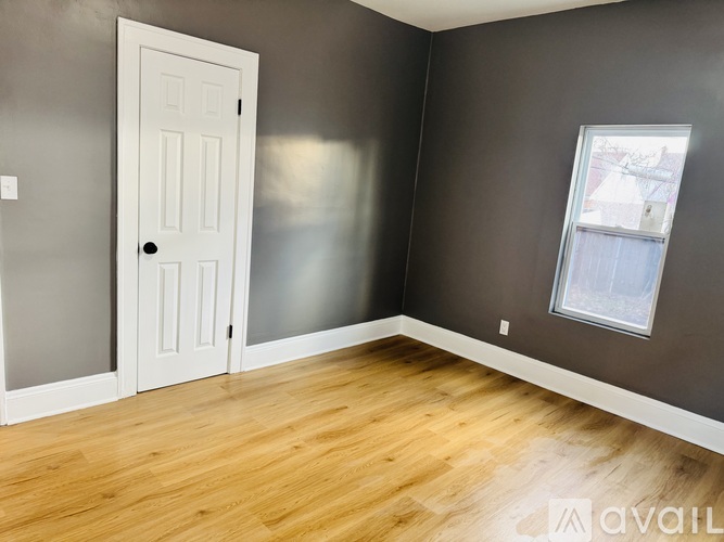 A room with a white door and a window with a view of a building outside.