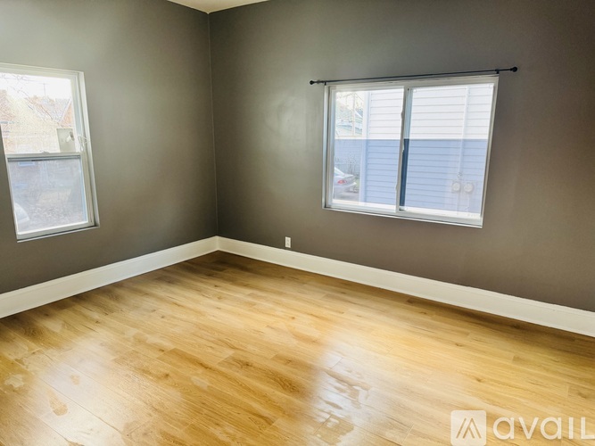 A room with wooden flooring and a window with blinds.