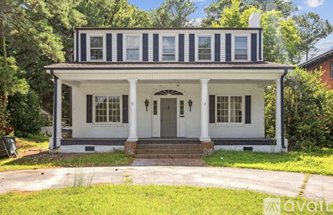 A white house with a black roof and a porch.