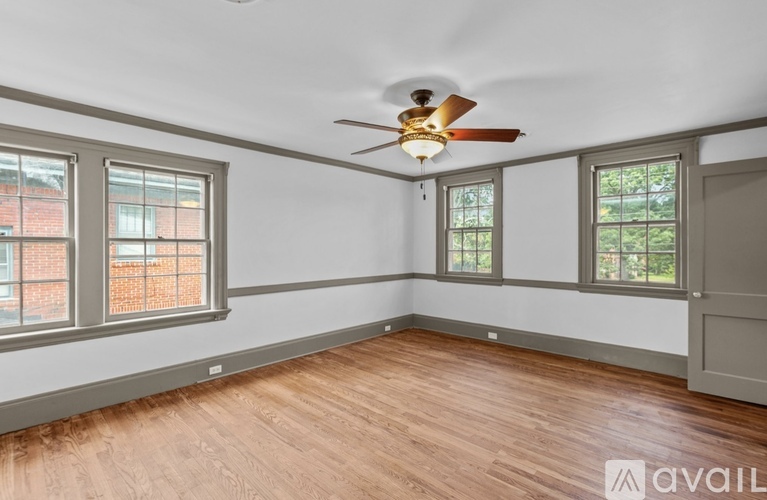 A room with a ceiling fan and three windows.