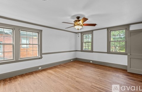 A room with a ceiling fan and three windows.