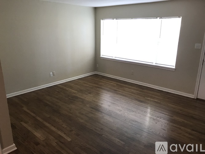 A room with wooden flooring and a window with blinds.