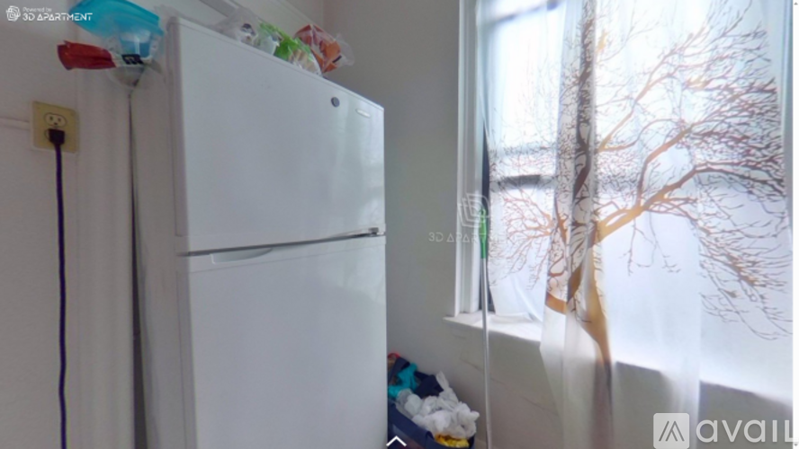 A white fridge in a room with a window showing a tree.