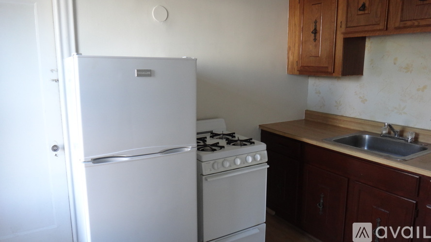 A white refrigerator and stove in a kitchen with wooden cabinets.