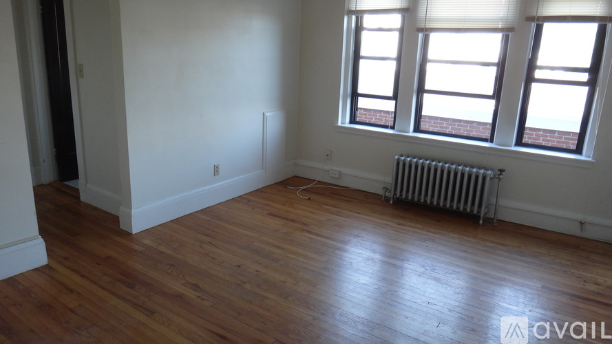 A room with wooden floors and a window with blinds.