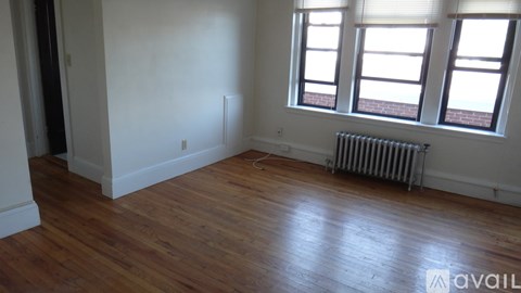 A room with wooden floors and a window with blinds.