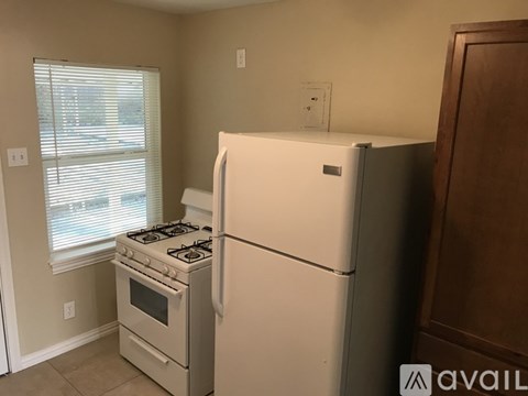 A white refrigerator sits next to a stove in a kitchen.
