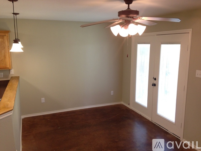 A room with a ceiling fan and a door leading to a hallway.