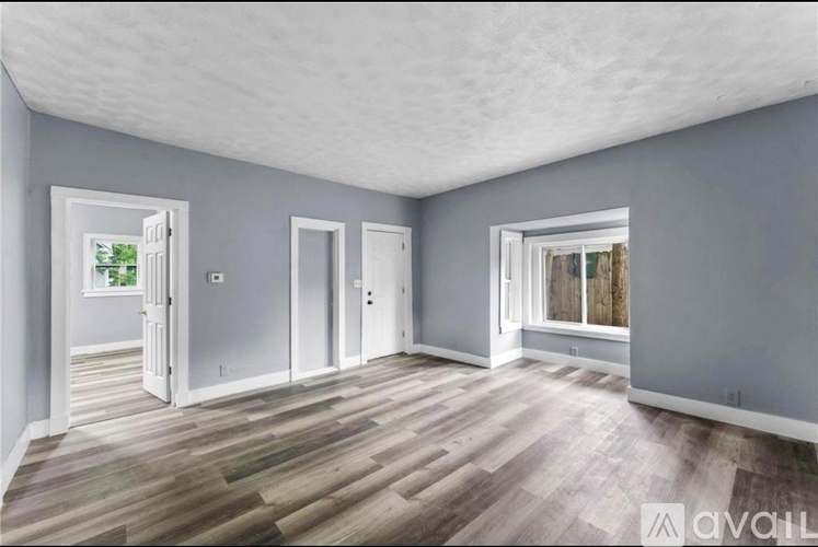 A spacious room with wooden flooring and white doors.