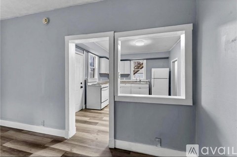 A kitchen with a refrigerator, sink, and cabinets is visible through a mirror.