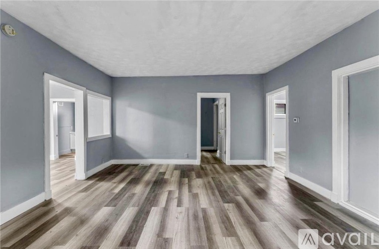 A room with wooden flooring and white walls, with a door on the right side.