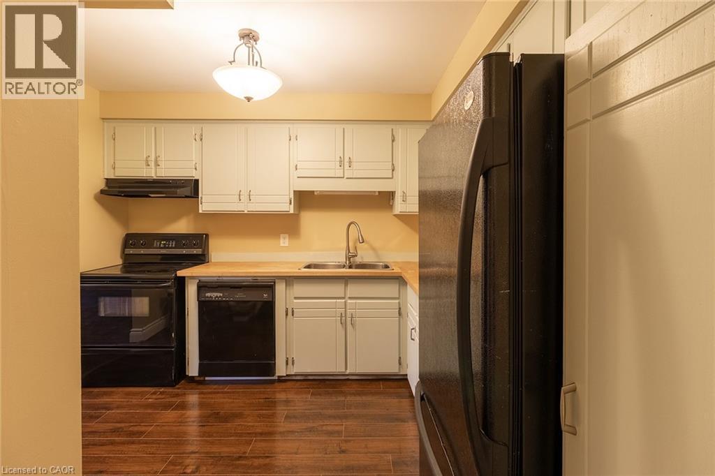 A kitchen with a black refrigerator and white cabinets.