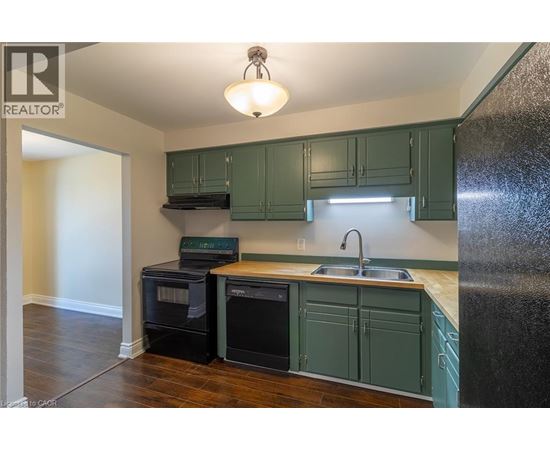 A kitchen with a black refrigerator and white cabinets.