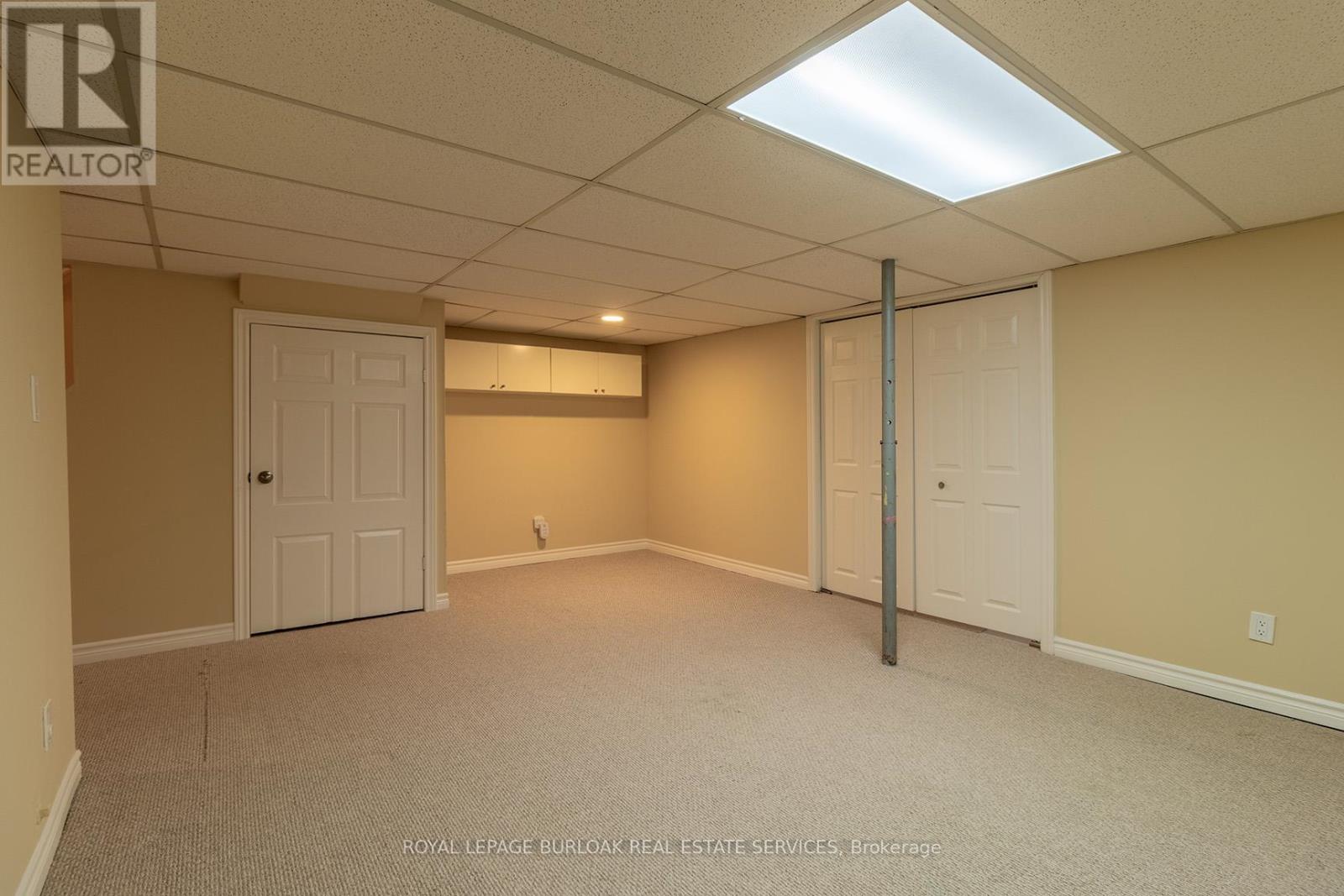 A spacious room with a carpeted floor and a white ceiling with a light fixture.