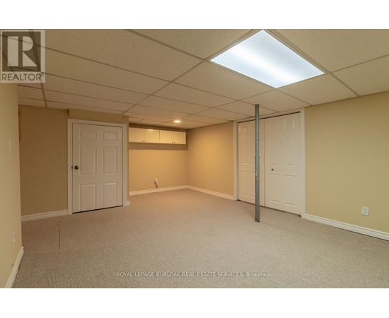 A spacious room with a carpeted floor and a white ceiling with a light fixture.