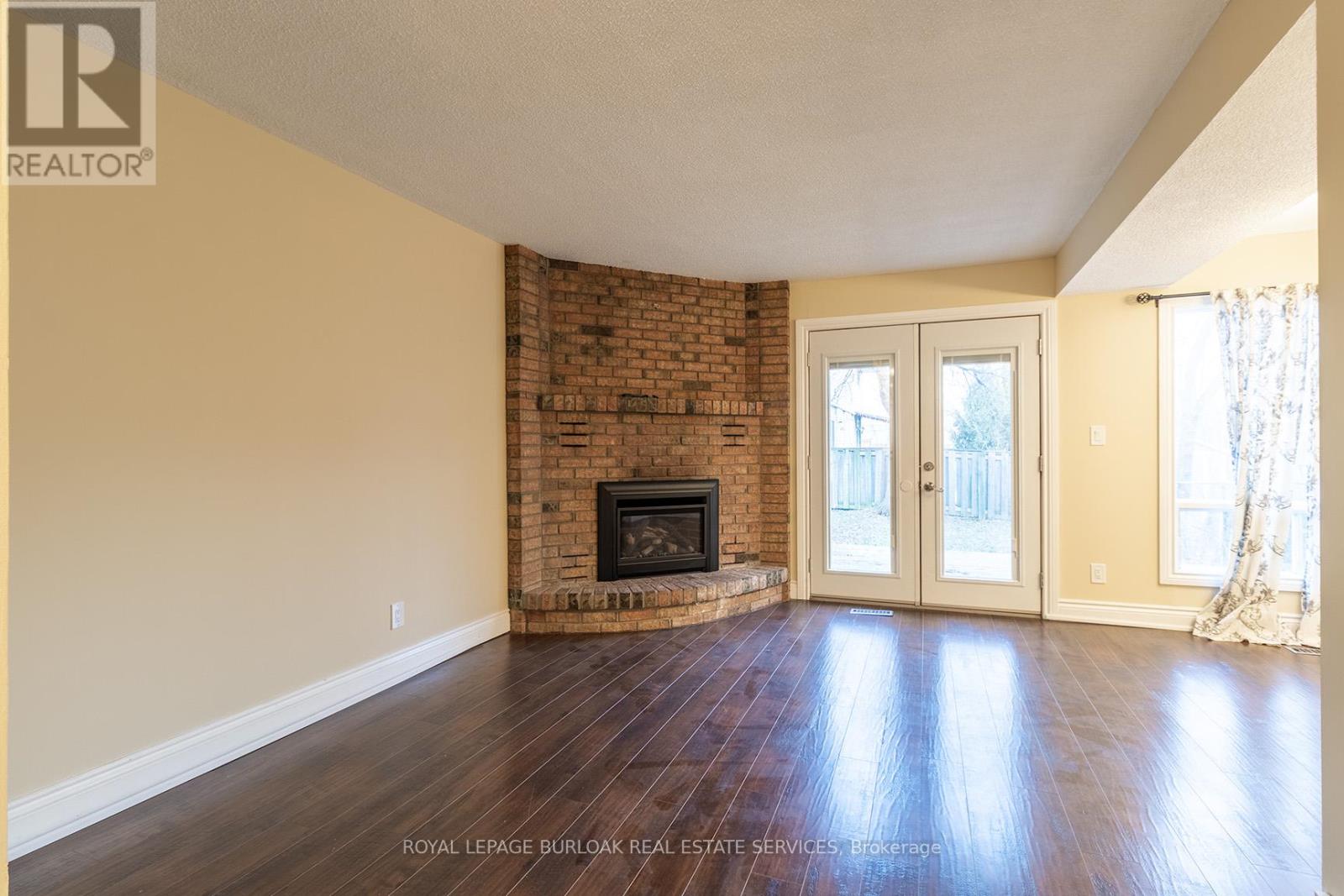 A living room with a fireplace and wood flooring.