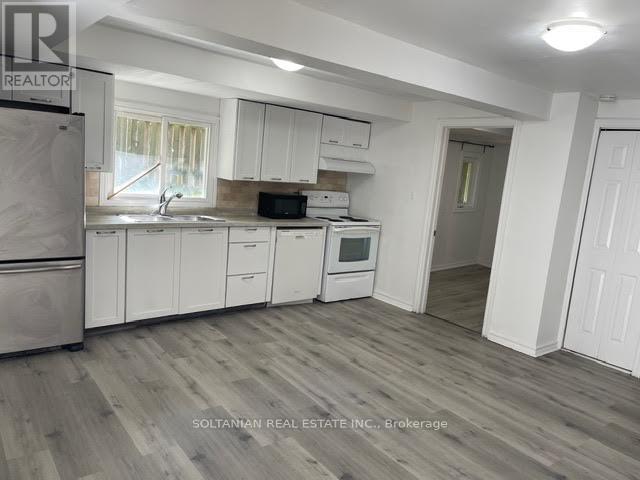 A kitchen with white cabinets and a refrigerator.