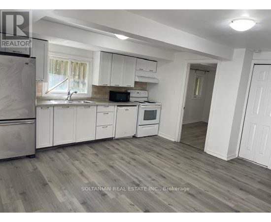 A kitchen with white cabinets and a refrigerator.
