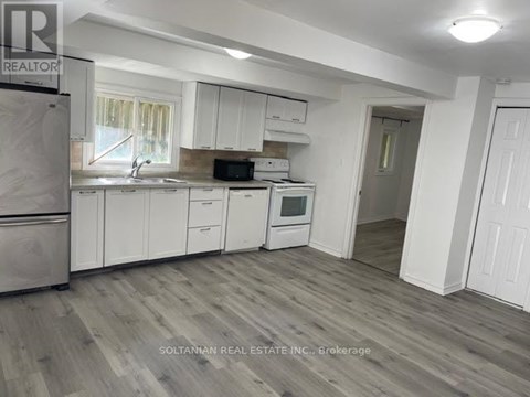 A kitchen with white cabinets and a refrigerator.