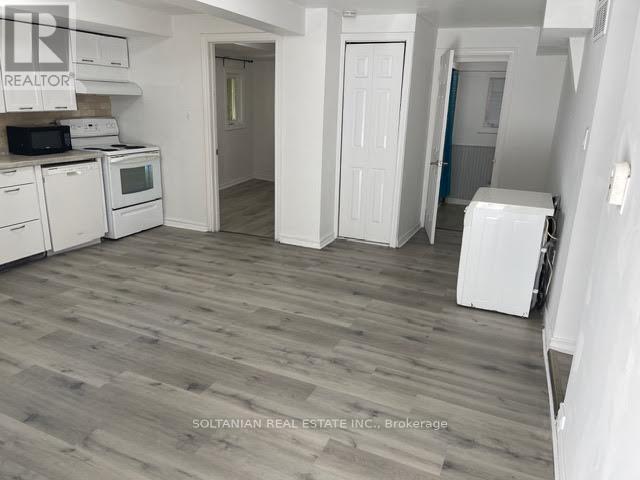A kitchen with white appliances and wooden floors.