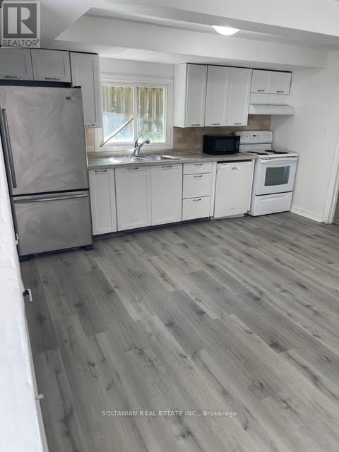 A kitchen with white cabinets and a wooden floor.